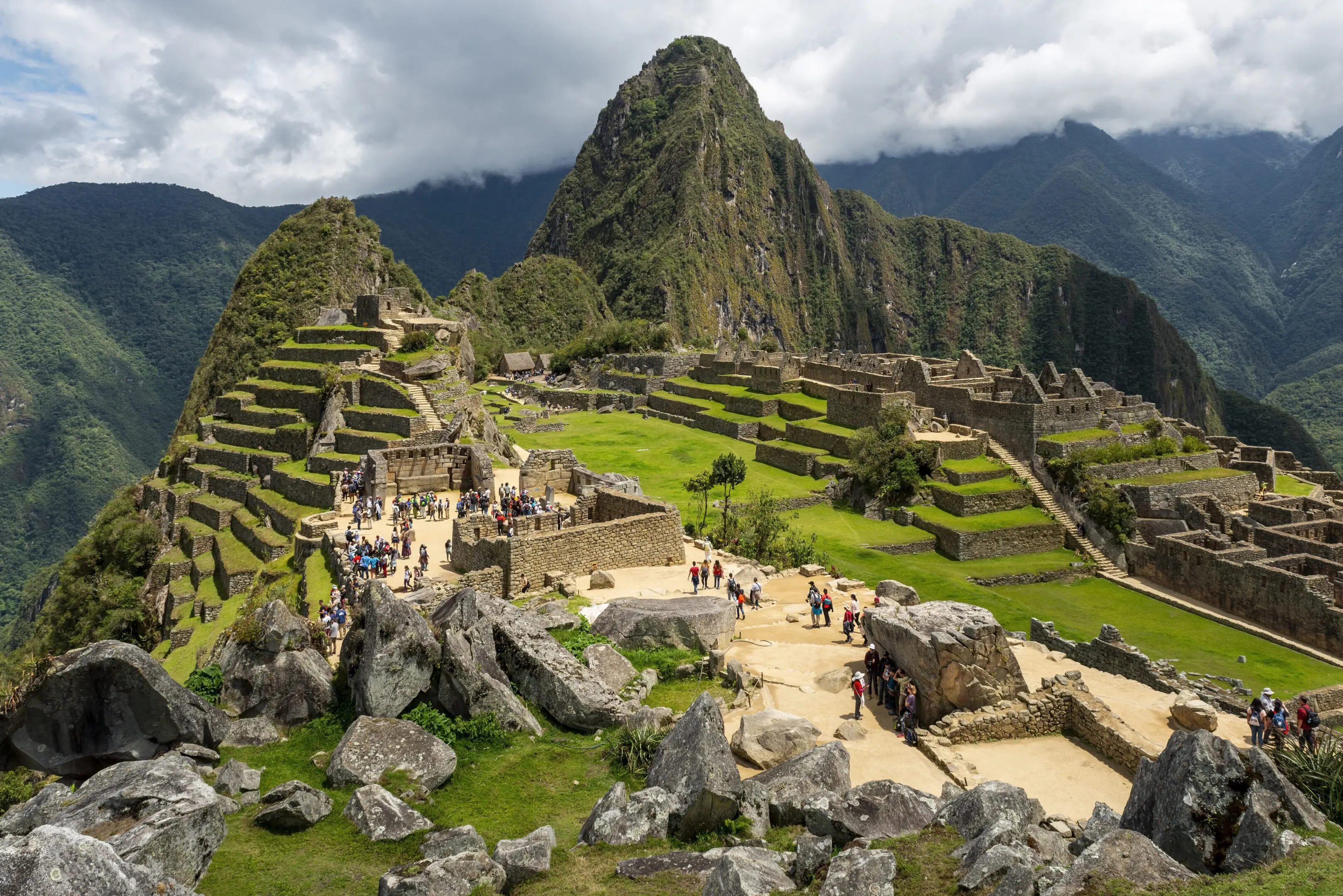 Machu Picchu ruins with tourists with dramatic clouds, Machu Picchu historical Sanctuary, Cusco, Peru.