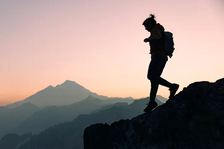 A Caucasian woman enjoys a hike on a beautiful Autumn day in Mount Baker area, Washington state, USA.  She walks along a ridge line at dusk. Healthy and enjoyable lifestyle.